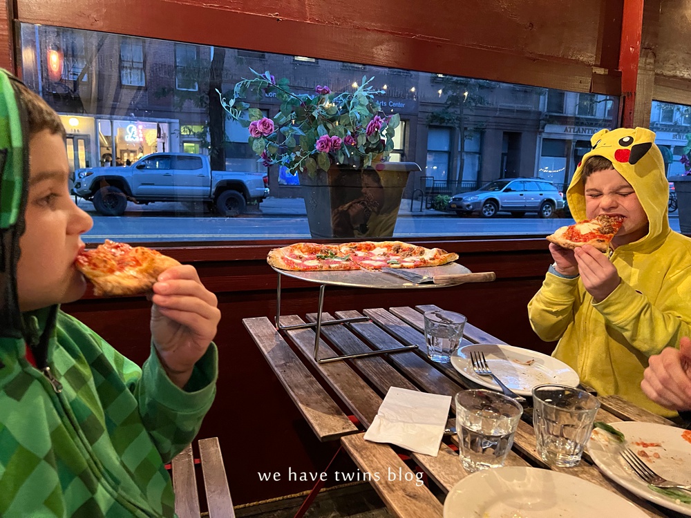 two kids enjoying pizza at luzzos bk brooklyn nyc